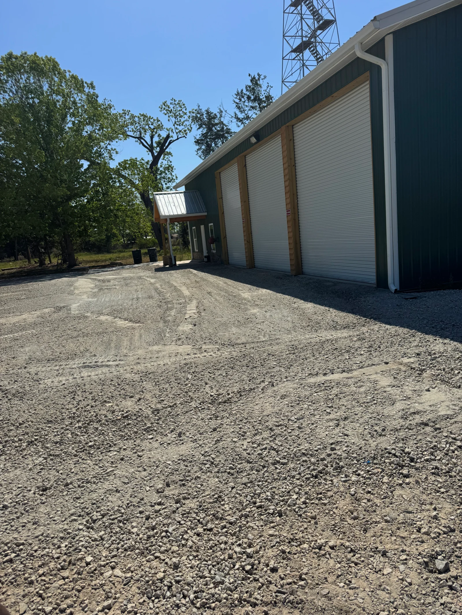 Gravel driveway and apron with crushed stone base in front of commercial building with roll-up doors