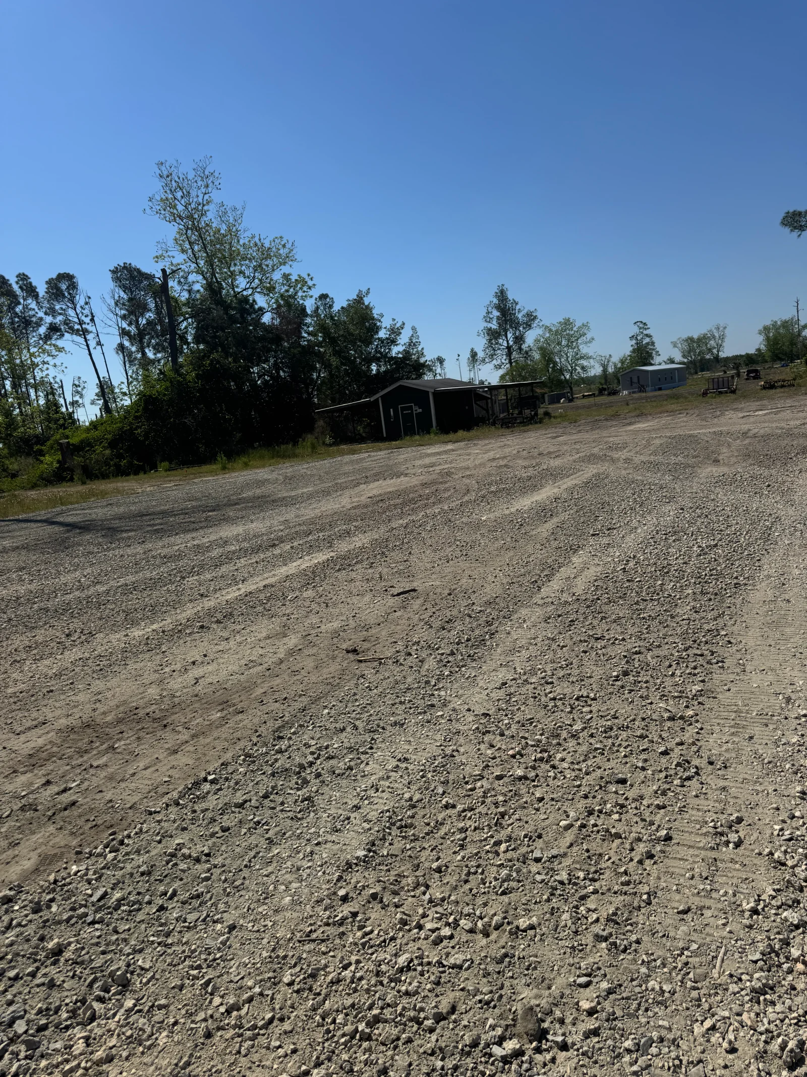 Compacted gravel driveway with crushed stone base and rural property structures