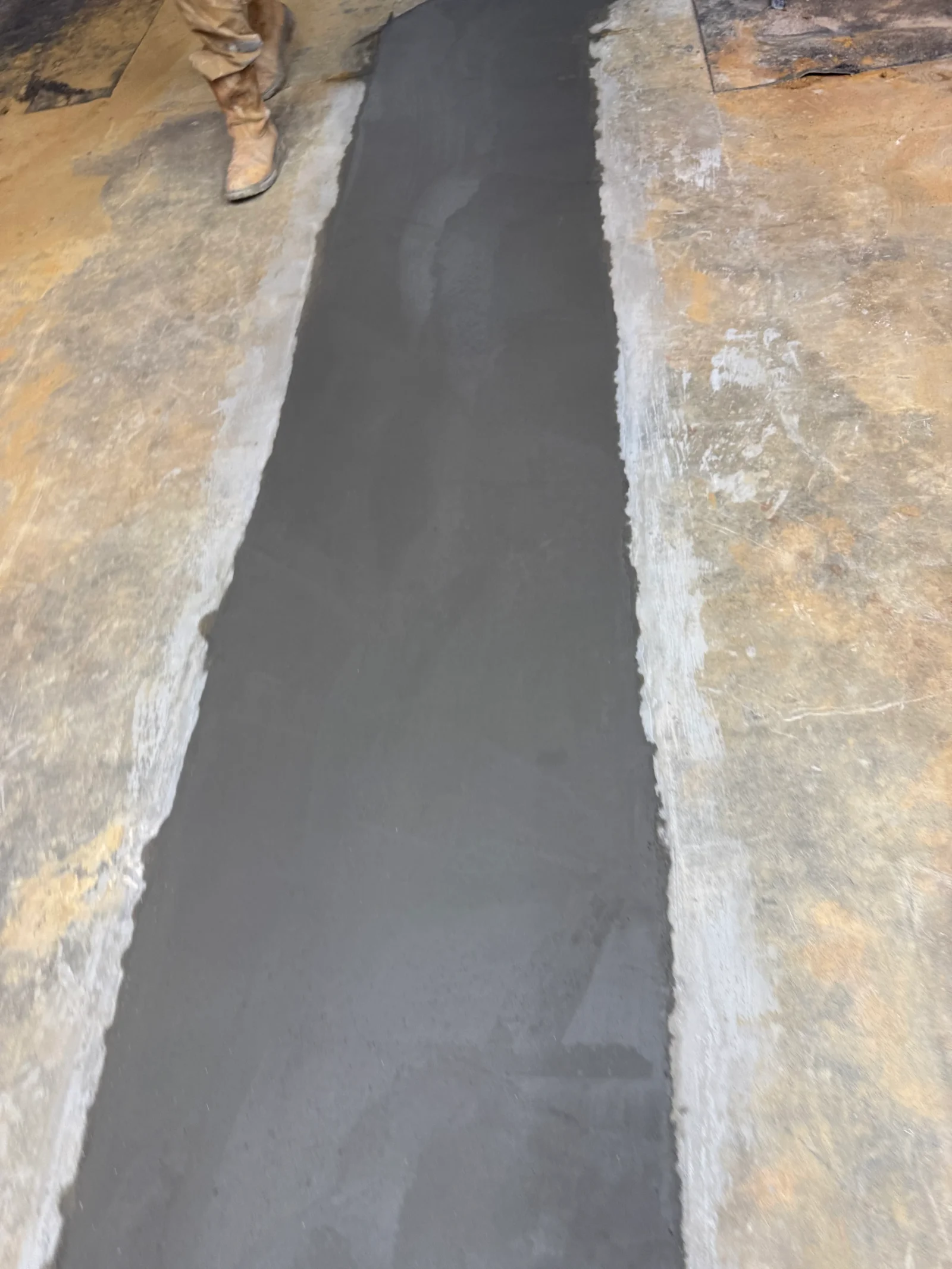 Newly poured concrete floor with clean edges and smooth finish between prepared surfaces