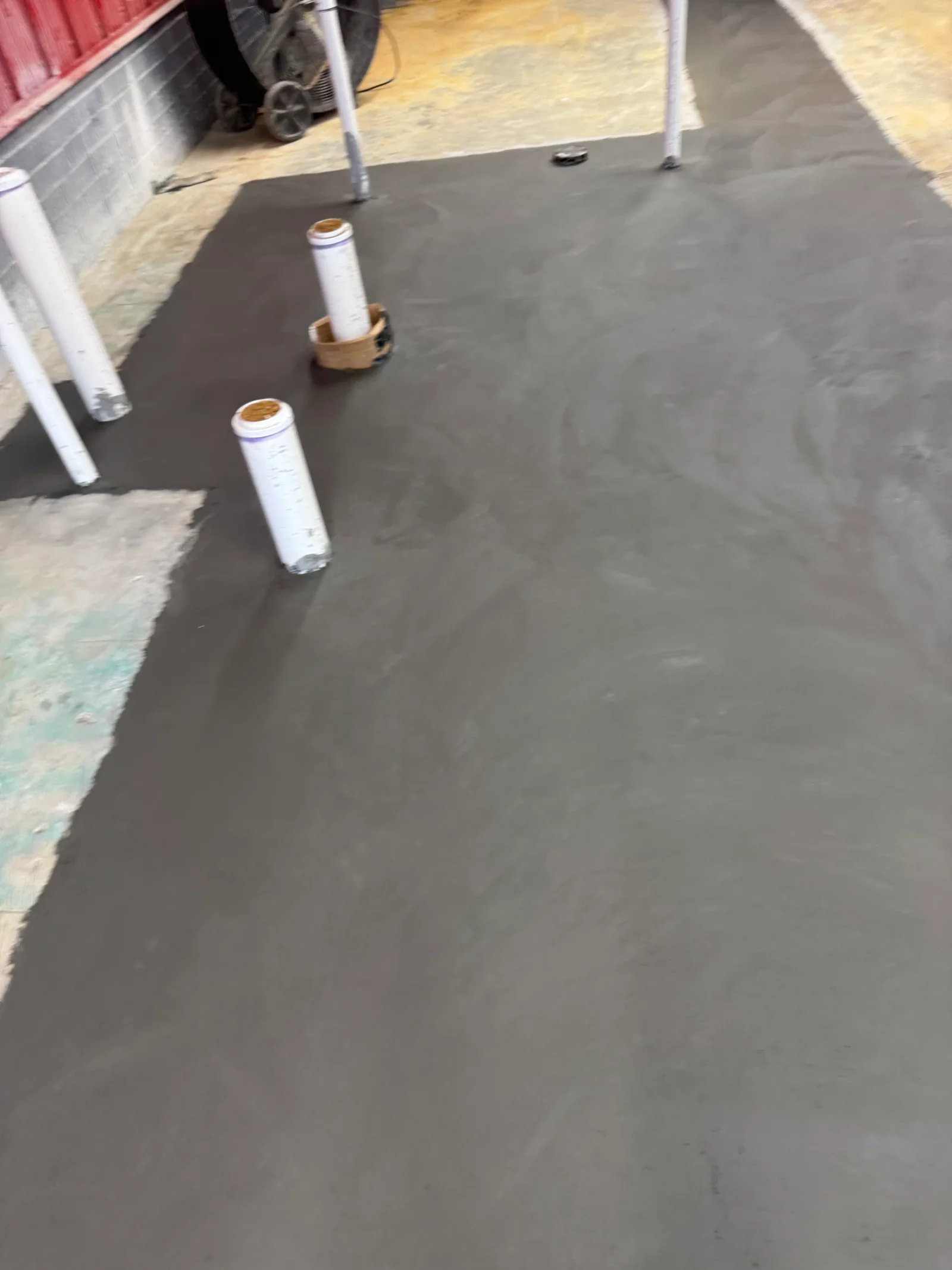 Dark rubber membrane roof with white fastener tubes and sealing materials on concrete substrate
