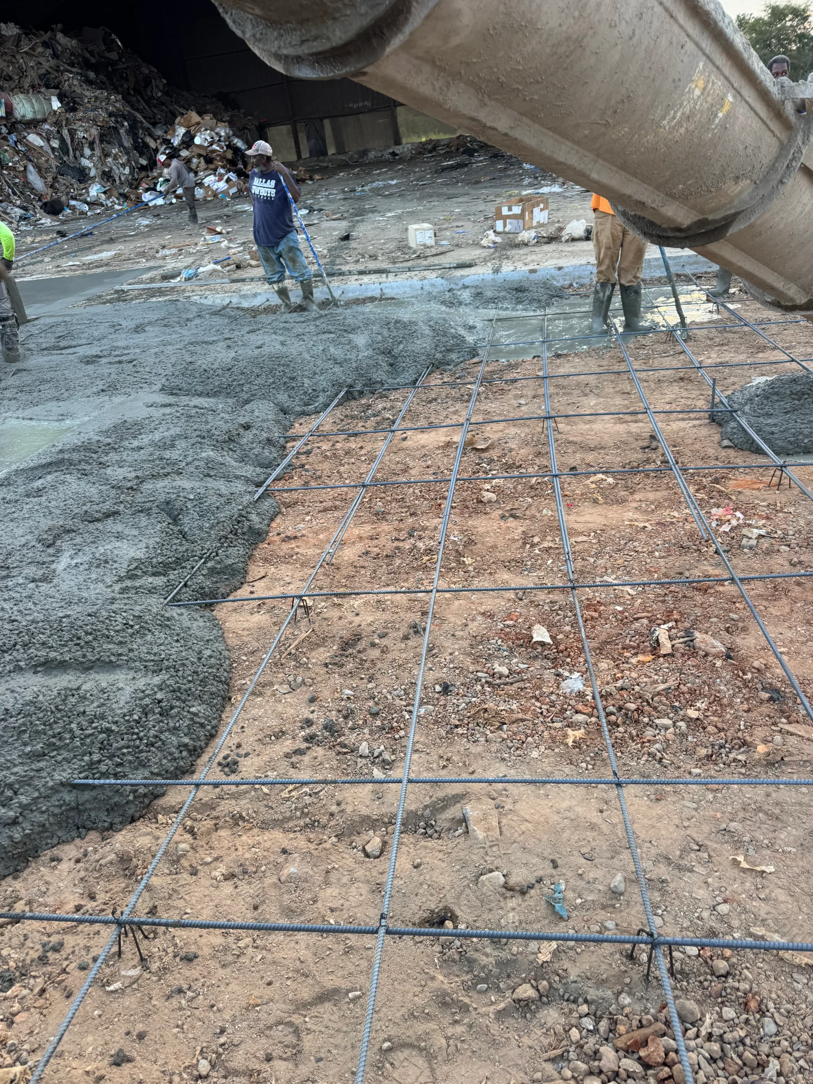 Concrete pump truck pouring foundation with rebar grid reinforcement on prepared subgrade