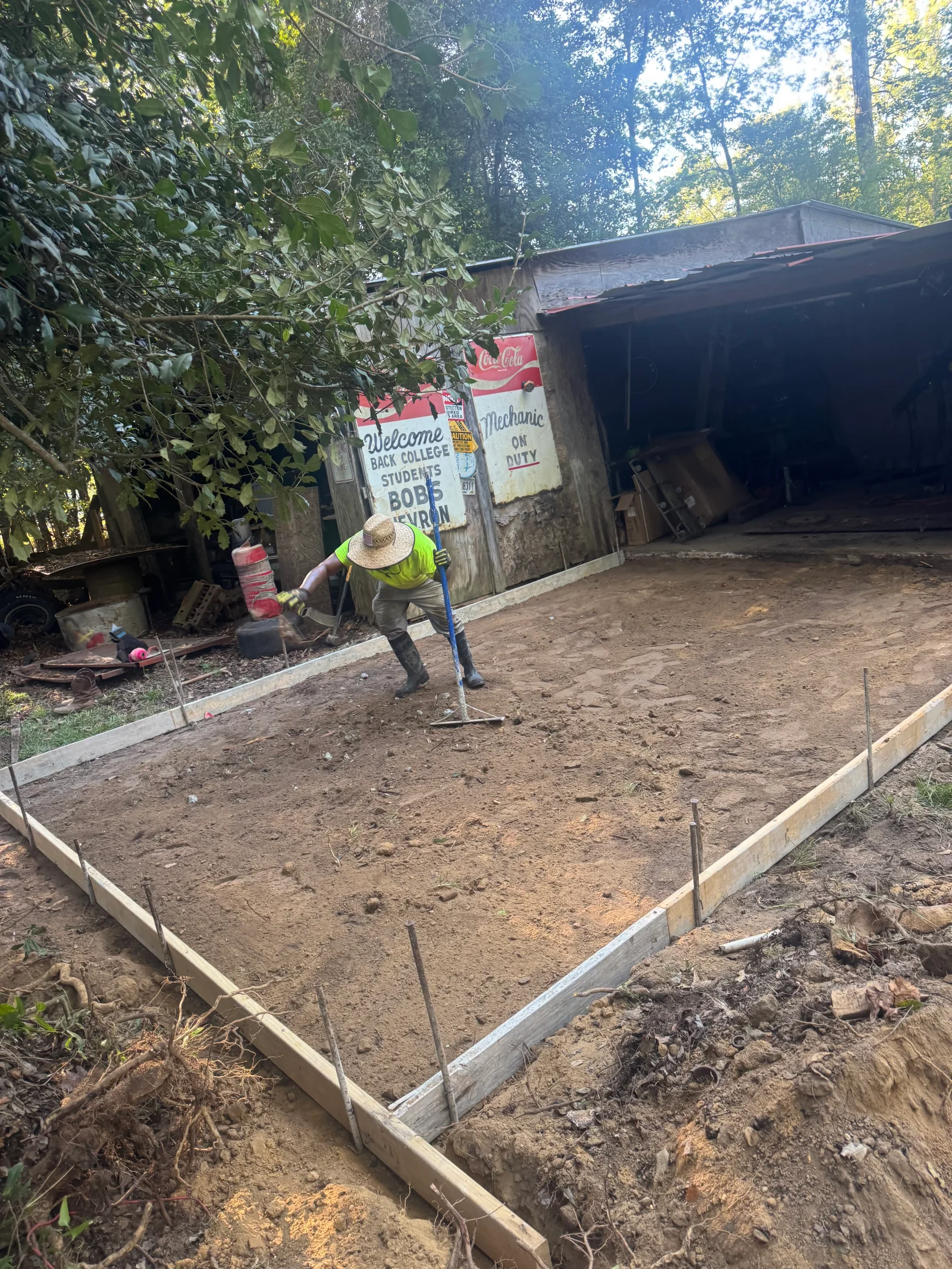 Wooden concrete forms and compacted soil foundation preparation with worker on site