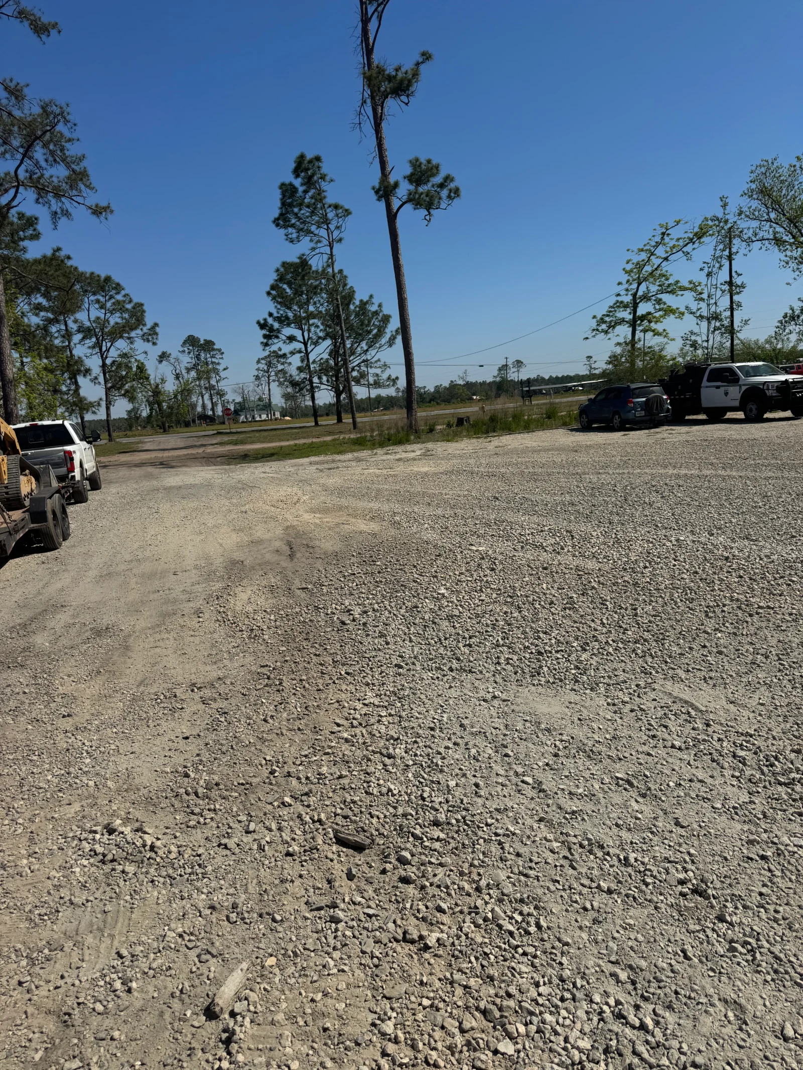 Compacted gravel lot with crushed stone base material and parked vehicles