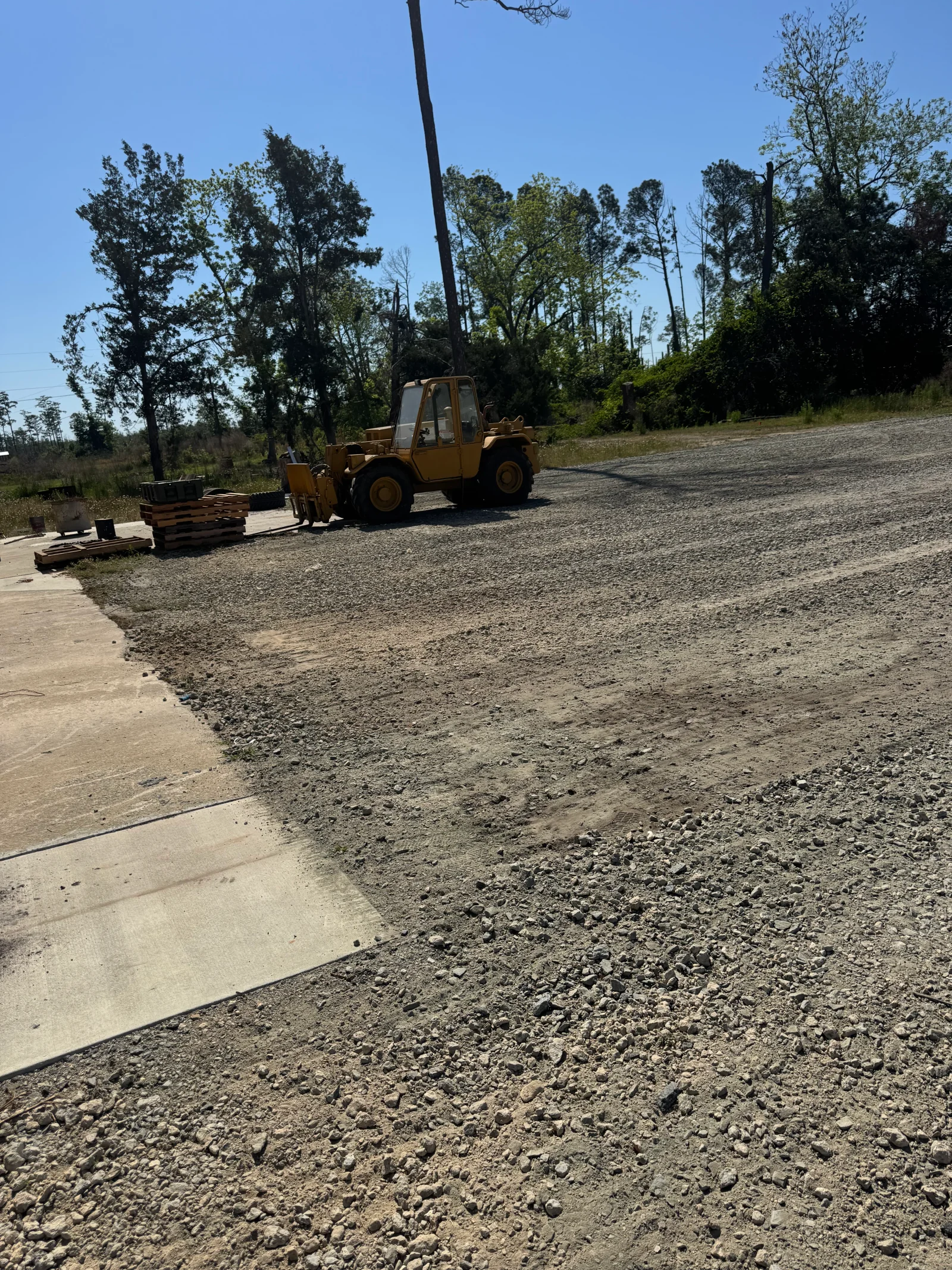 Wheel loader spreading and compacting gravel base with concrete forms and crushed stone